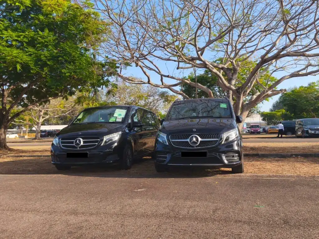 Two clean, professional black Mercedes-Benz vans parked under trees, illustrating the high vehicle standards that ensure My Singapore Driver is safe.