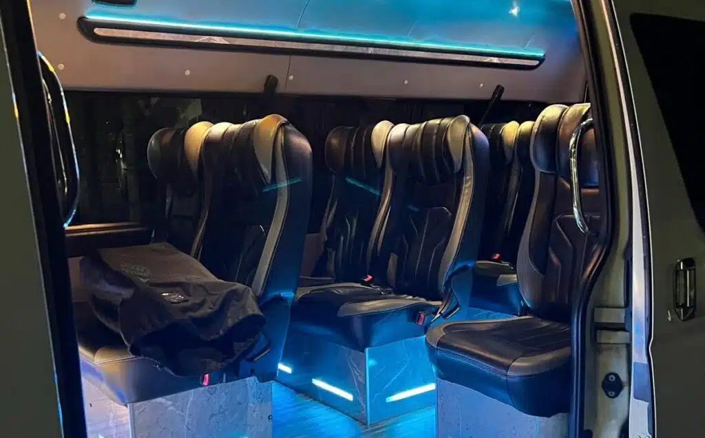 Token2049 Singapore 2026 Side Event Transport featuring a premium shuttle van interior with comfortable leather passenger seats and ambient blue lighting.